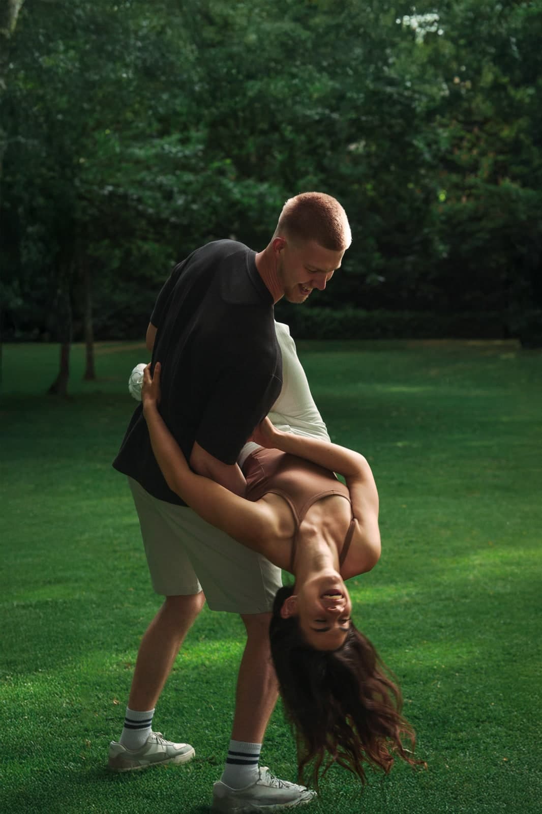 Couple on a lawn, one dipped all the way back and laughing upside down