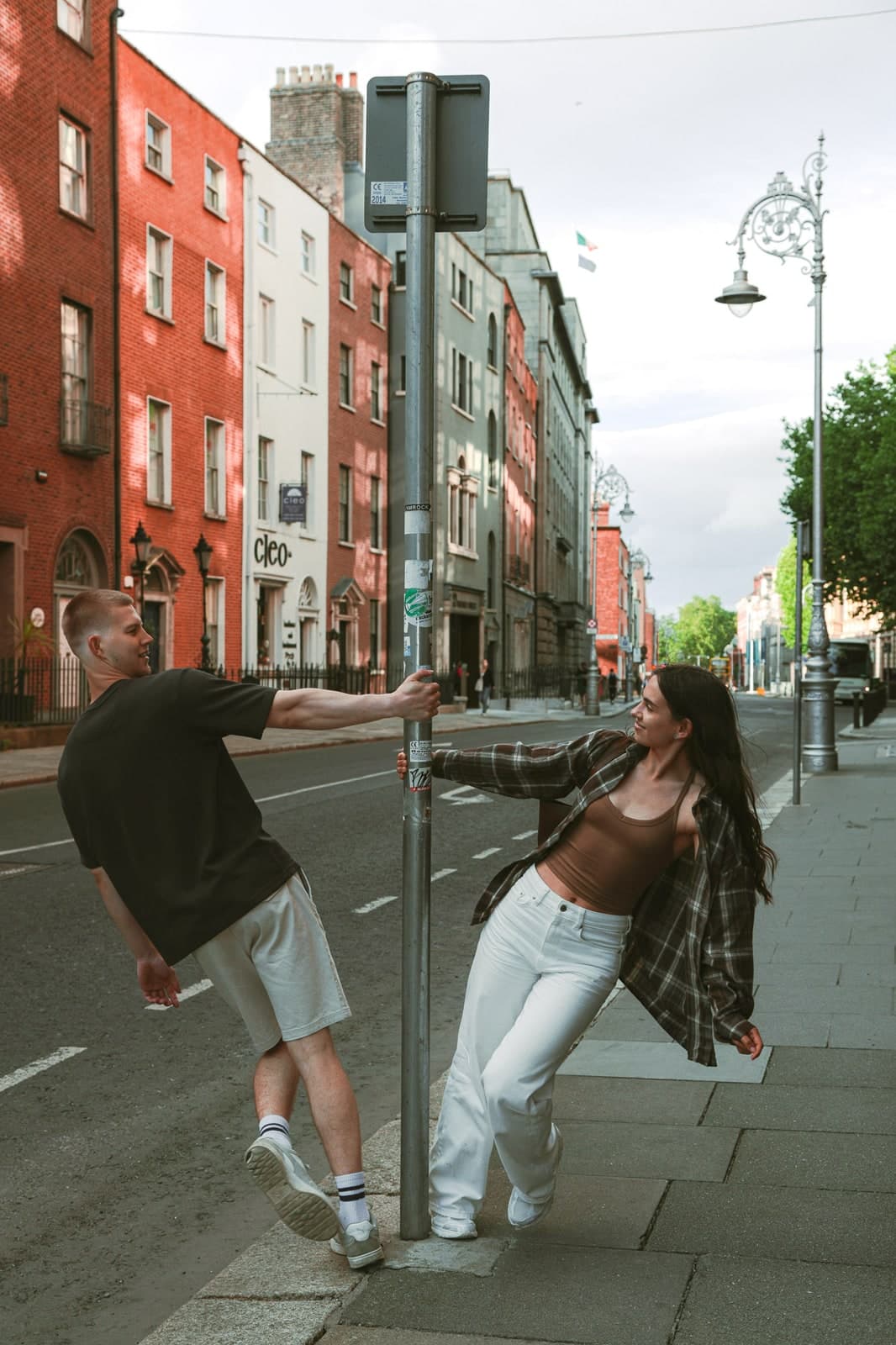 Couple swinging around a lamppost on a street of red-brick Georgian houses