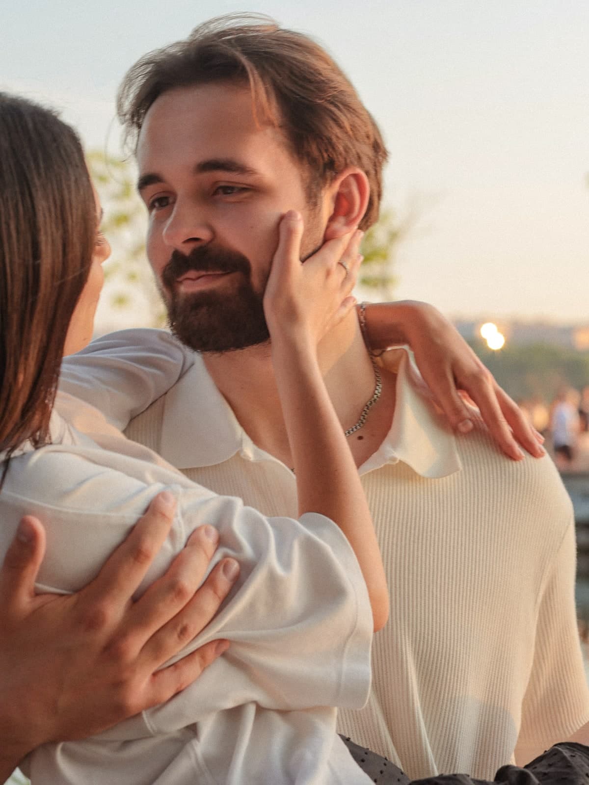 Close together in golden evening light, a hand resting on a bearded cheek