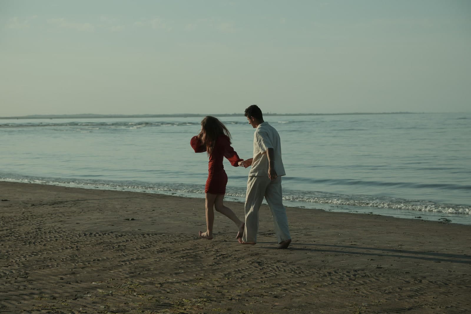 Couple walking hand in hand along the shoreline at low tide