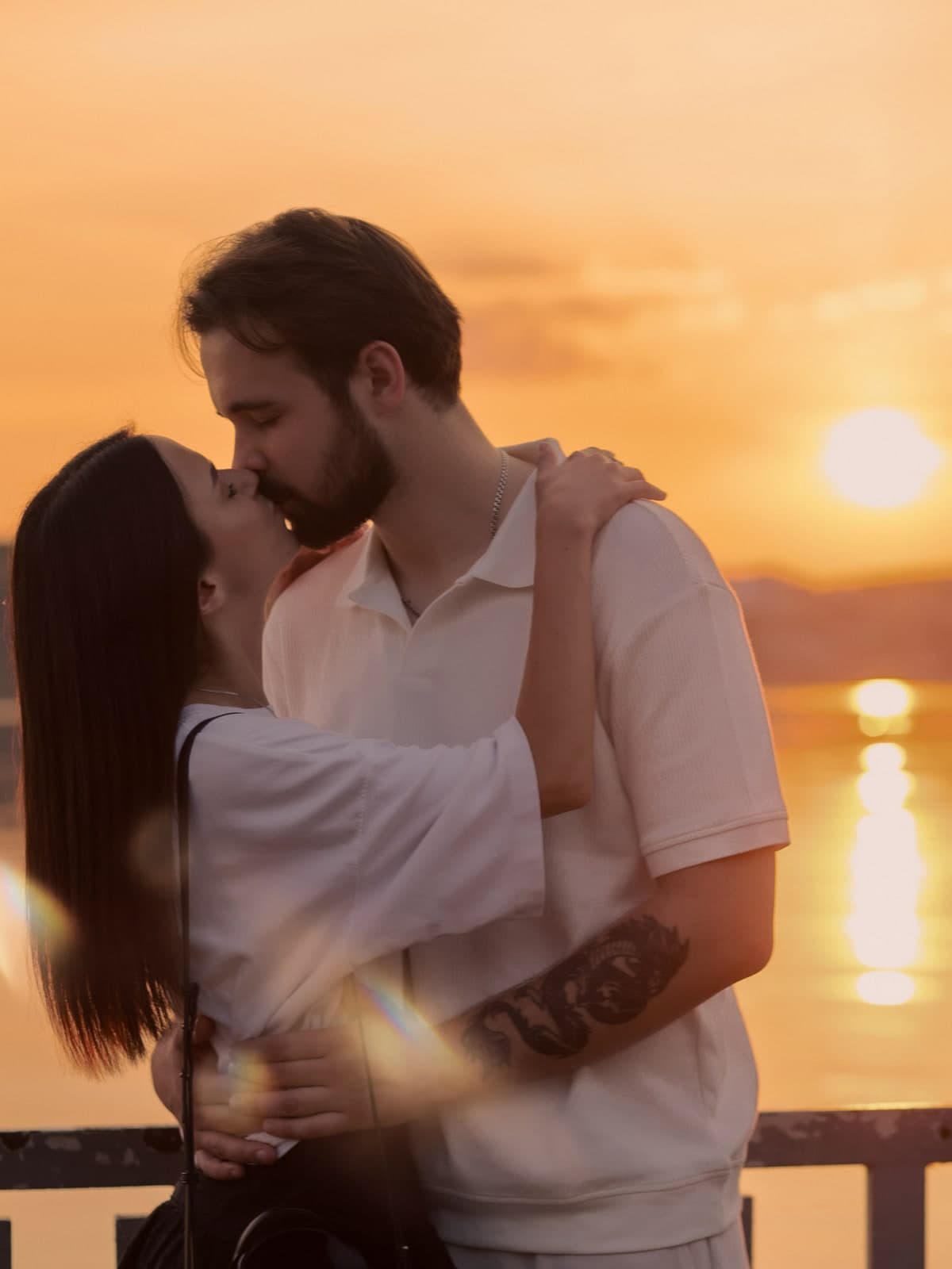 A kiss at sunset by the water, the sun reflected in the lake