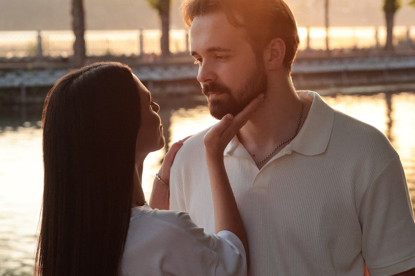 A hand on a cheek, standing close by the water in the evening light