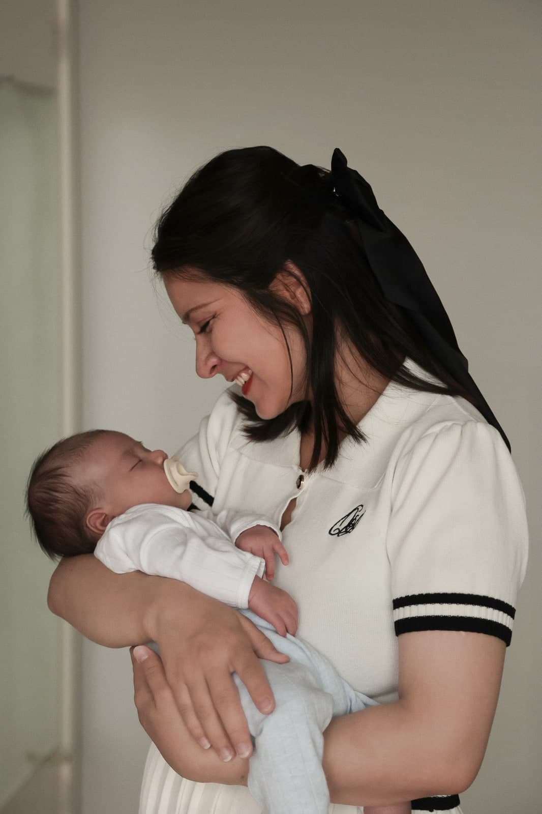 A parent smiling down at a sleeping newborn held close