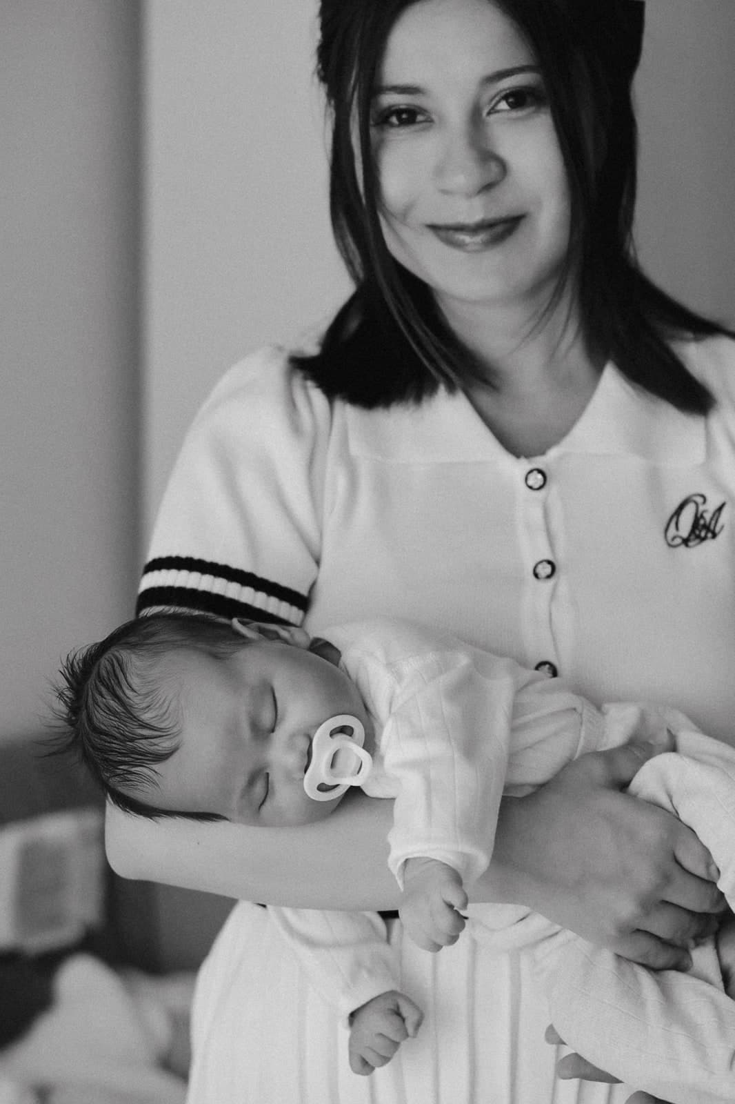 Black-and-white portrait of a smiling parent cradling a sleeping newborn