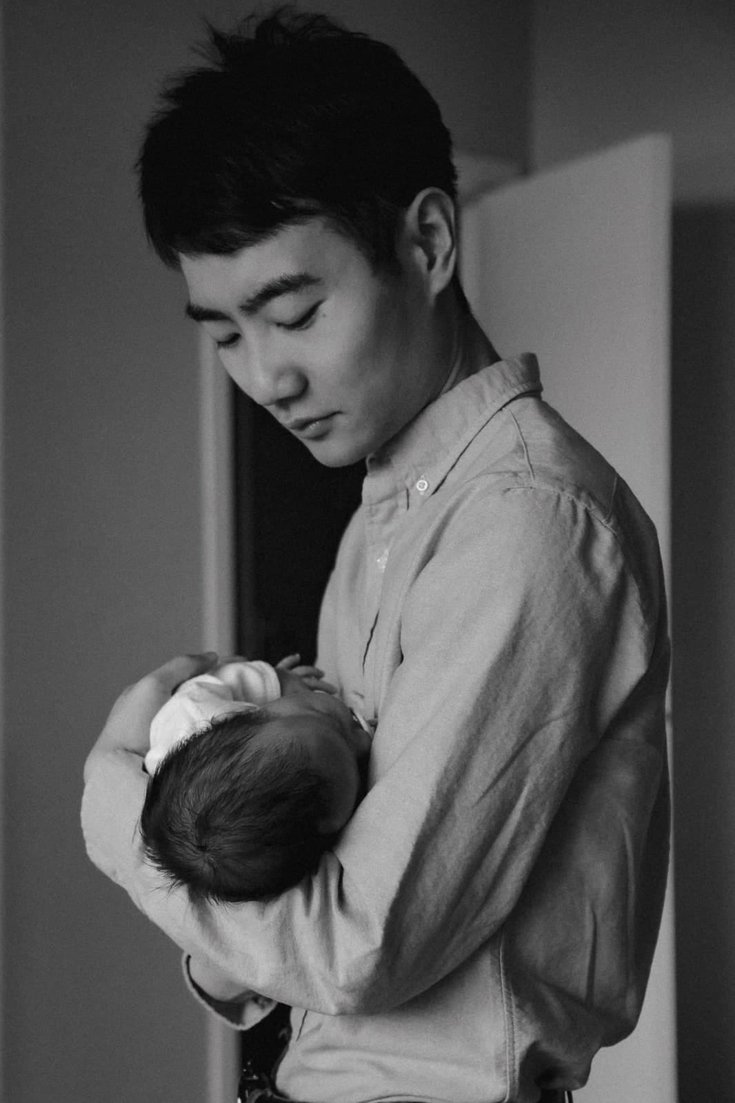 Black-and-white portrait of a parent looking down at the newborn in their arms