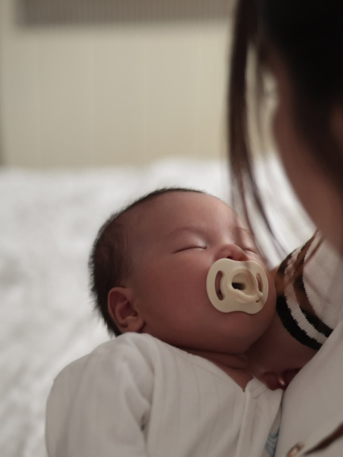 Close-up of a newborn asleep on a parent's shoulder