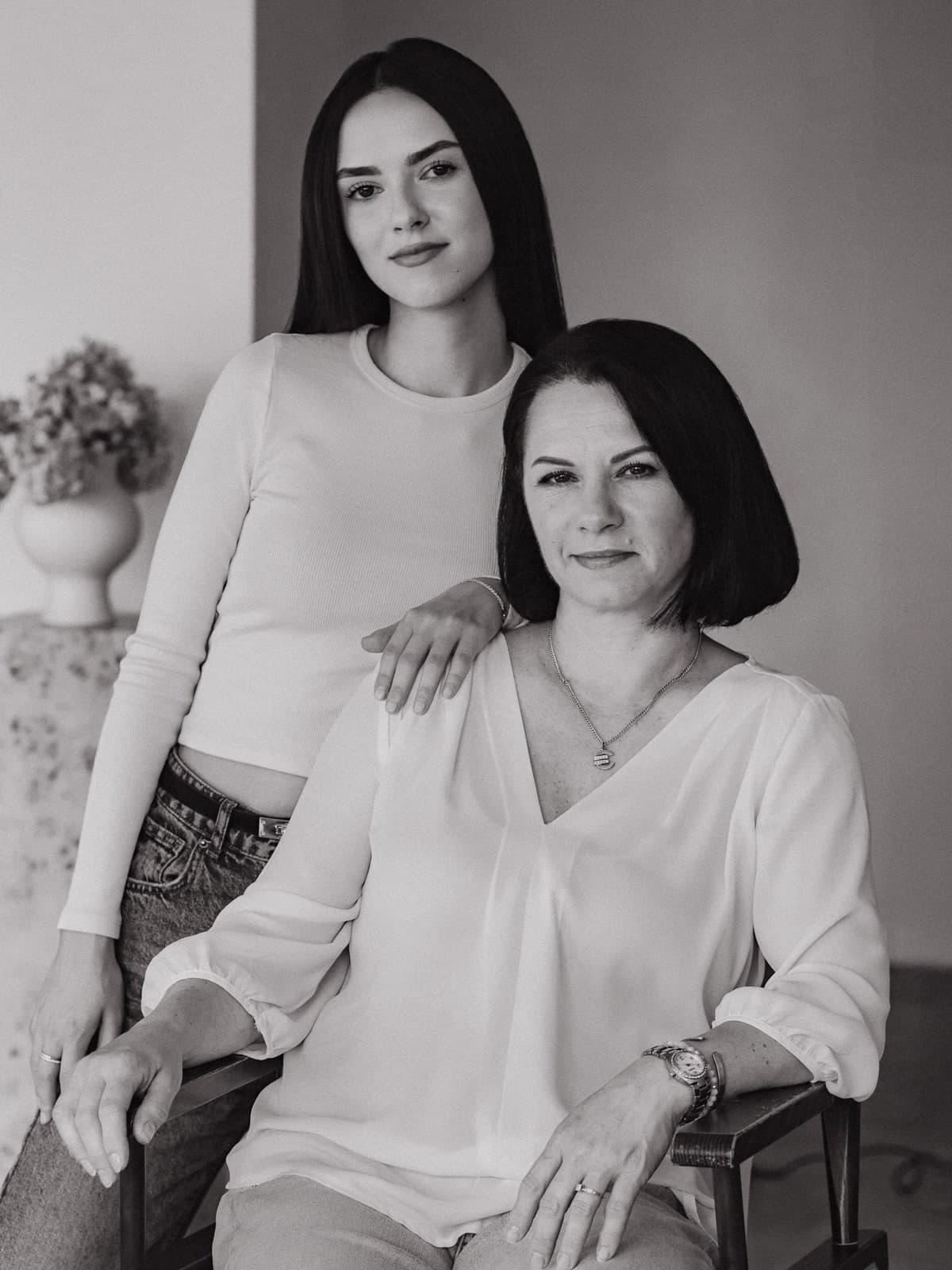 Black-and-white studio portrait of two generations, one seated, the other standing behind