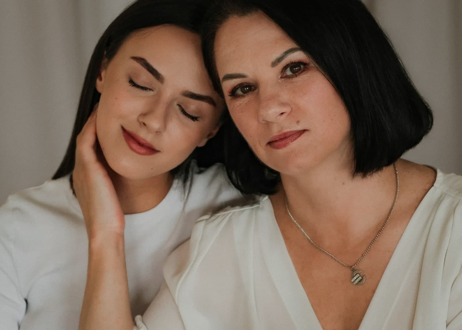 Heads together in soft studio light, one with eyes closed