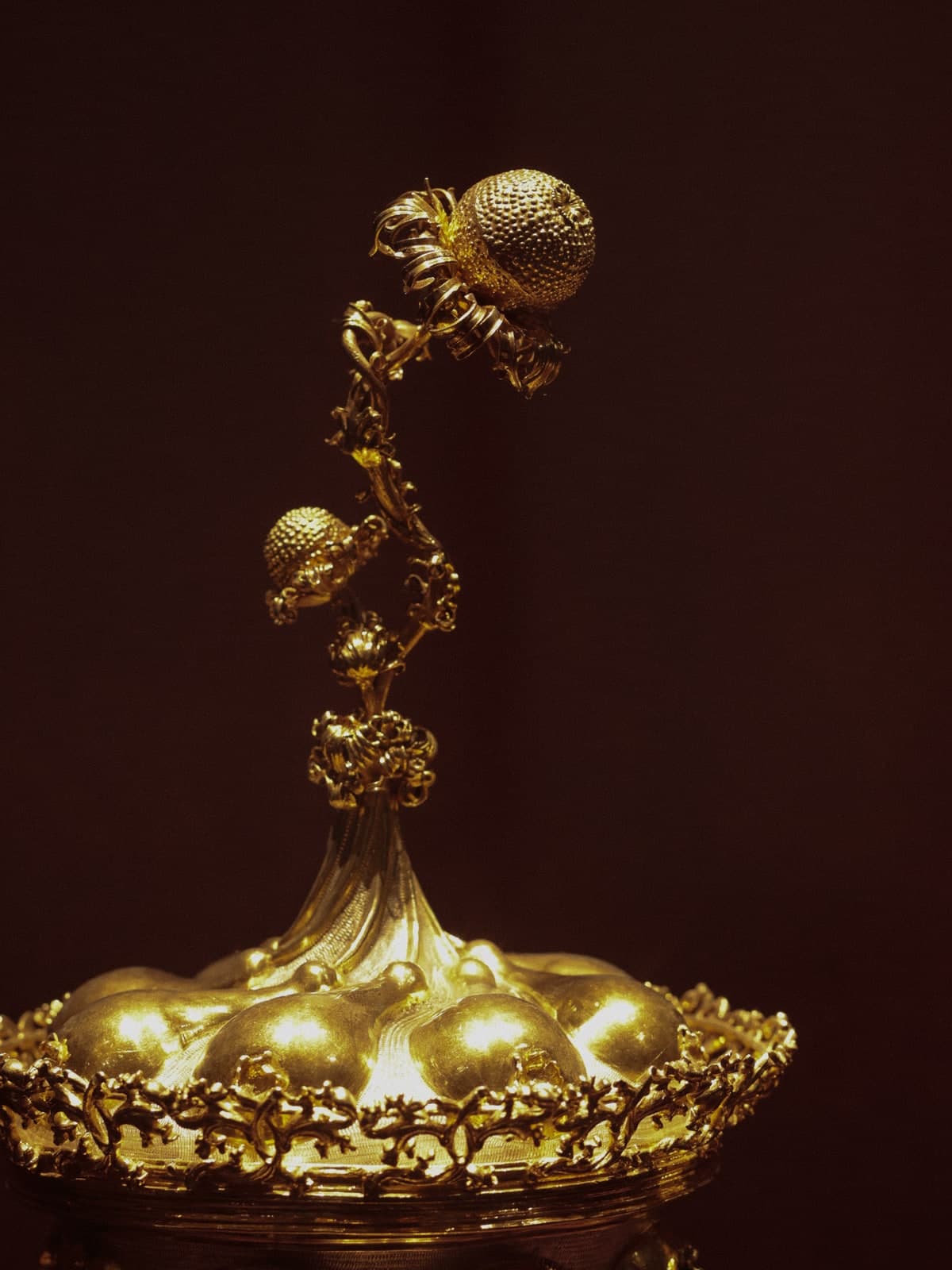 A gilded ornament with tiny climbing figures, glowing against the dark