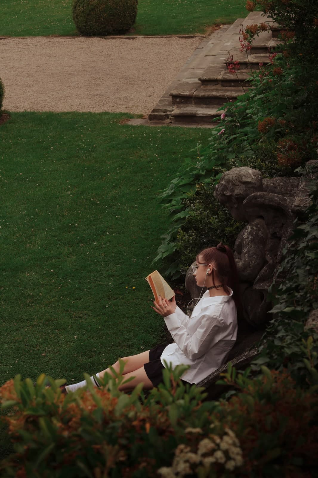 Reading on the grass against an old stone wall in a formal garden