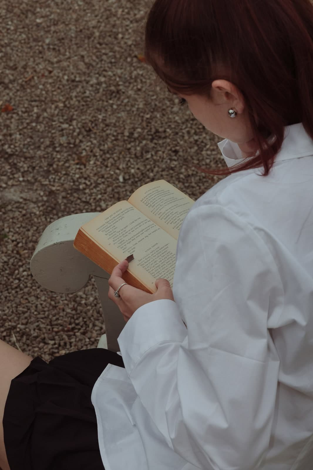 Over-the-shoulder view of an open paperback, red hair and a white shirt