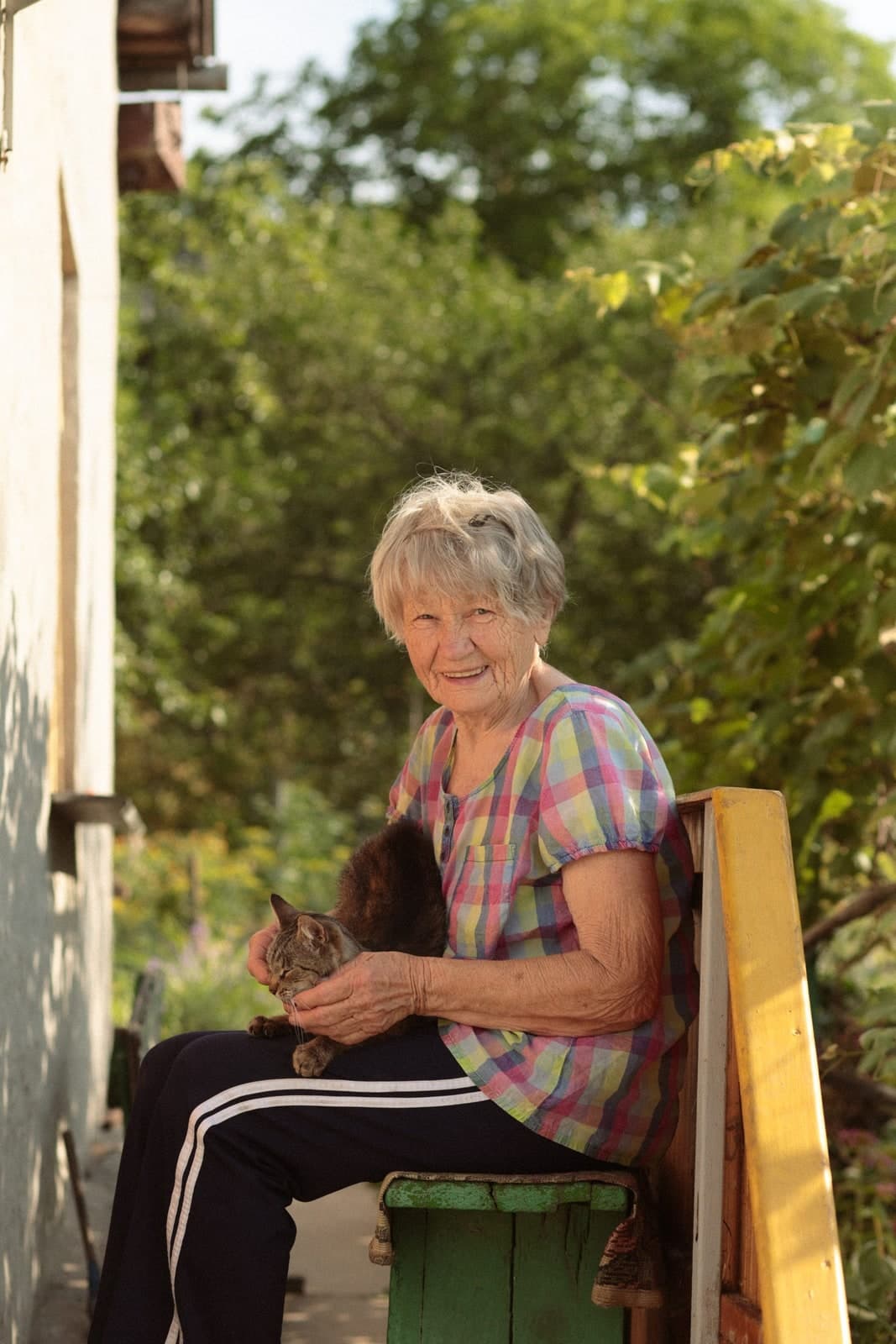 Smiling on a garden bench in the sun with a cat on the lap
