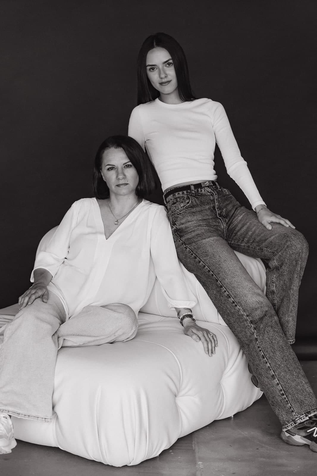 Black-and-white studio portrait of two generations on a white armchair